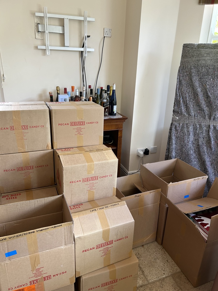 Packed removal boxes stacked and labelled in a living room ready for house move in Devon