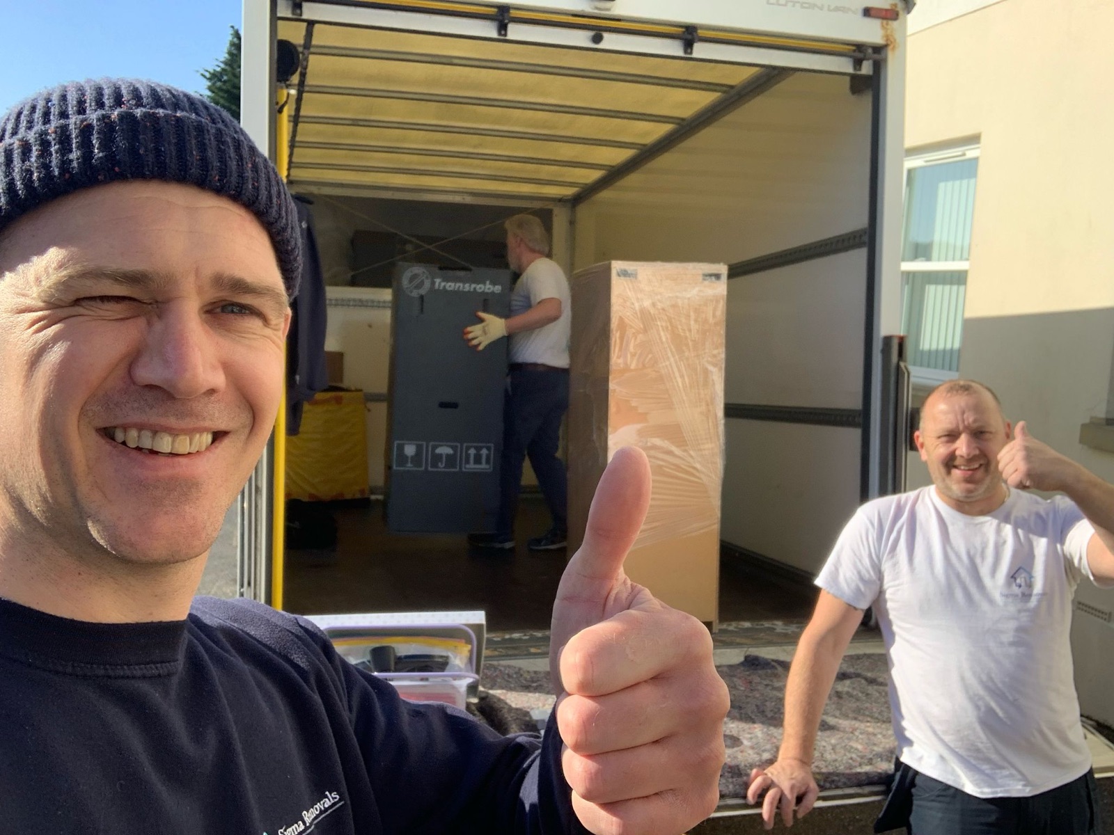 Sigma Removals team giving thumbs up while loading wardrobe boxes into the removal van